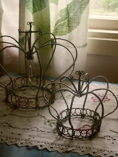 two wire baskets sitting on top of a doily next to a window sill