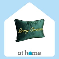 a green pillow with the words merry christmas written on it in gold lettering, against a light blue background