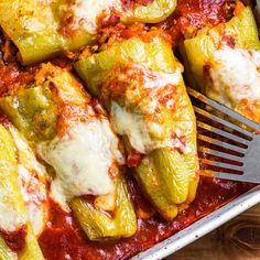 a casserole dish with zucchini, cheese and sauce on the side