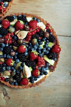 a pie topped with berries and blueberries on top of a marble counter