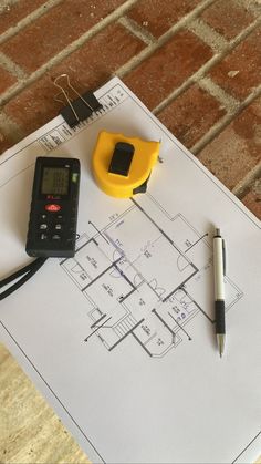 a blueprint with a calculator, ruler and pen sitting on top of it