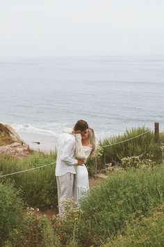 a man and woman standing next to each other near the ocean