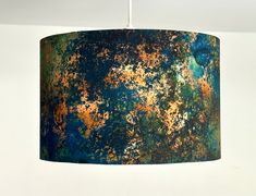 a blue lamp shade with rusted paint on it hanging from a ceiling fixture in a room