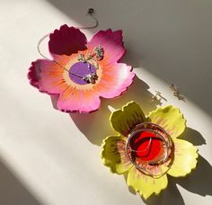 two flower shaped dishes sitting next to each other on a white counter top with sunlight coming through the window