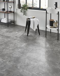 a bathroom with grey tile flooring and white walls in the background is a window