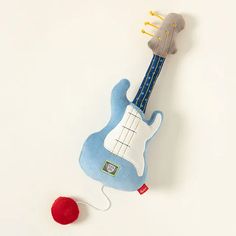 an electric guitar toy with a red ball on the floor next to it and a white background