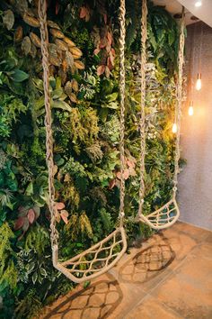 a living wall with plants and lights hanging from it's sides, in front of a tiled floor