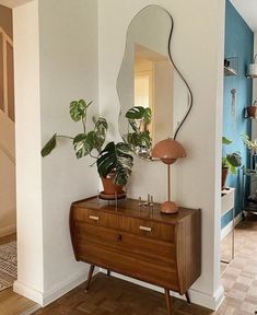 a mirror and some plants on a dresser in a room with blue walls, wood floors and hardwood flooring