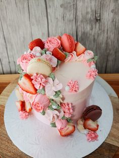 a pink cake decorated with flowers and strawberries