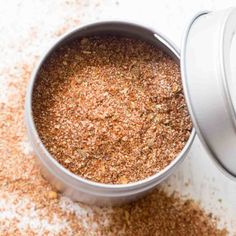 an open can filled with ground spices on top of a table next to a spoon