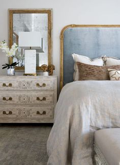 a bedroom with a bed, dresser and mirror on the wall next to each other