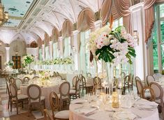 a banquet hall with tables, chairs and flowers in vases on the table top