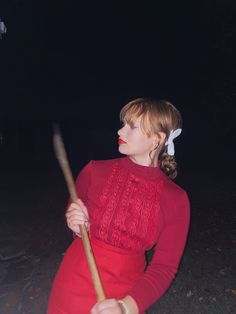 a woman in a red dress holding a stick