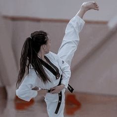 a woman is doing karate on the floor with her arms in the air and one hand up