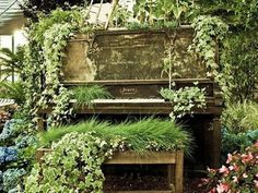 an old piano is surrounded by plants and flowers