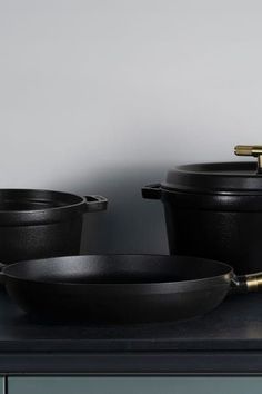 three black pots and pans sitting on top of a counter