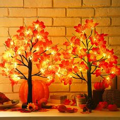 two lighted trees on a mantle with pumpkins