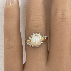 a woman's hand with a pearl and diamond ring on top of her finger