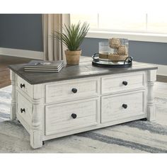 a white coffee table with drawers and a potted plant sitting on top of it