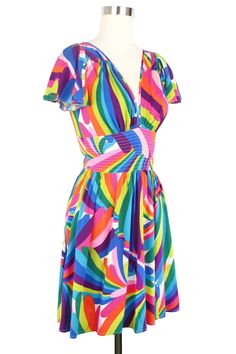 Share in our mission to bring color and happiness to people everywhere with our new Rainbow Bright collection! This 1960s original print is revived in slinky soft stretch rayon. Summer lovin’ styles from dreamy dresses to cool caftans. Deep V-neck Front and Back Flutter Sleeves Fitted Waistband Invisible Back Zipper Gathered Skirt Above the Knee Pockets Fabric: Stretch RayonLining: Waist Lined in Stretch Rayon Rainbow Bright, Clothing And Textile, Antique Clothing, Dreamy Dress, Summer Lovin, Gathered Skirt, Modern Outfits, Clothing Size Chart, Flutter Sleeves