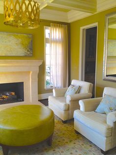 a living room filled with furniture and a fire place under a chandelier in front of a window