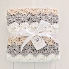 two crocheted blankets with a white ribbon tied around the edges and tag on top