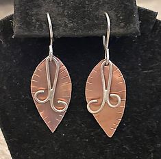 Introducing our exquisite handmade copper earrings enhanced by sterling silver wire dangles and light incisions that create texture along the edges of the leaves. Crafted with utmost care and attention to detail, these sweet  earrings showcase a delicate leaf design that gracefully hangs from your ears.  The earwires are stainless steel.  They measure 1 3/4" from top to bottom.   The combination of the copper and silver metals creates a mesmerizing contrast, adding a touch of class to any outfit Handmade Leaf-shaped Metal Jewelry, Nature-inspired Silver Copper Earrings, Copper Leaf-shaped Jewelry Gift, Handmade Leaf-shaped Metal Earrings, Gold Leaf-shaped Copper Jewelry, Sweet Earrings, Green Hats, Handmade Copper, Copper Earrings