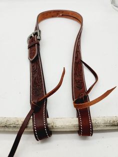 a pair of brown leather straps sitting on top of a white surface