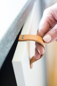 a hand is holding onto the handle of a cabinet door with a rubber band on it