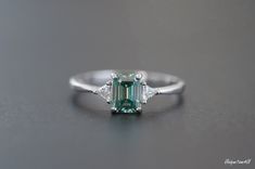 Gorgeous and delicate Green Moissanite  ring  ， Nice gift for girlfriend/wife or Mother It will come with GRA Certificates， So please Don't worry about quality， Every stone is The Best！ Basic information  Stone： Top grade green Moissanite  Color Grade：D color Clarity Grade ： VVS1 Stone Shape: Emerald Cut 5*7mm Stone weight ：1.0 ct Metal Materials: Sterling Silver And Platinum Group Metal Multi-Layer Plating (Platinum Group Metals Multi-layer Plating is an Advanced Process, Very Safe and Comforta Green Trillion Cut Promise Ring, Green Vvs Clarity Rings For Proposal, Emerald Cut Sapphire Ring With Vs Clarity For Wedding, Green Diamond Ring With Vs Clarity For Wedding, Emerald Cut Sapphire Promise Ring, Vs Clarity, Emerald Cut, Moissanite Rings, Emerald Ring, Promise Rings