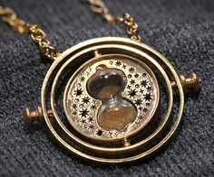 a gold necklace with a circular design on it's chain, sitting on top of a black surface