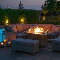 a fire pit sitting on top of a patio next to a swimming pool at night