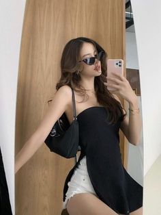 a woman taking a selfie in front of a mirror wearing a black top and white shorts