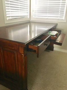 an office desk with drawers underneath it in front of two windows that have white shutters