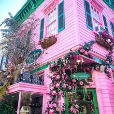 a pink building with green shutters and flowers on the outside