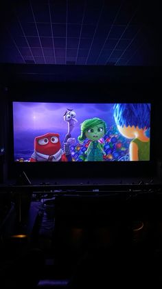 a large screen in a dark room with some lights on and the character from inside out