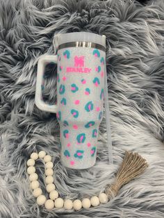 a white and blue cup sitting on top of a fur covered floor next to a tassel