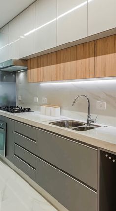 a modern kitchen with stainless steel appliances and white counter tops, along with wooden cabinets