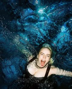 a woman is floating in the water with her mouth open and eyes wide open as she looks at the camera