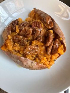 a white plate topped with sweet potatoes covered in pecans