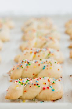 some cookies with sprinkles are lined up on a baking sheet