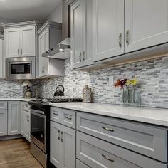 a kitchen with gray cabinets and white counter tops