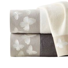 two towels with white flowers on them, one is gray and the other is brown