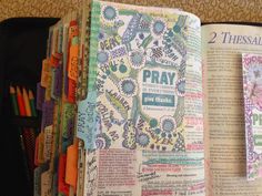 an open bible with the word pray printed on it and several colored pencils next to it