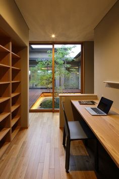 an office with wooden floors and open bookshelves in front of a sliding glass door