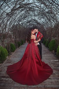 a man and woman in red dress standing under an archway