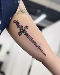 a person with a tattoo on their arm holding a cross and a knife in the other hand