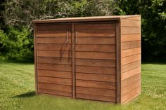 a wooden storage shed sitting in the grass