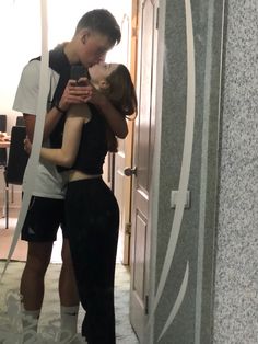 a man and woman standing in front of a door with their arms around each other