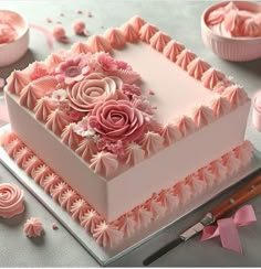 a square cake with pink icing and flowers on it